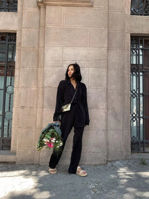 Kadın dış giyim modelleri ve çeşitlerinden siyah takım bulunur elinde çiçek buketi ve ayağında krem rengi ayakkabısı olan kadının üzerinde.